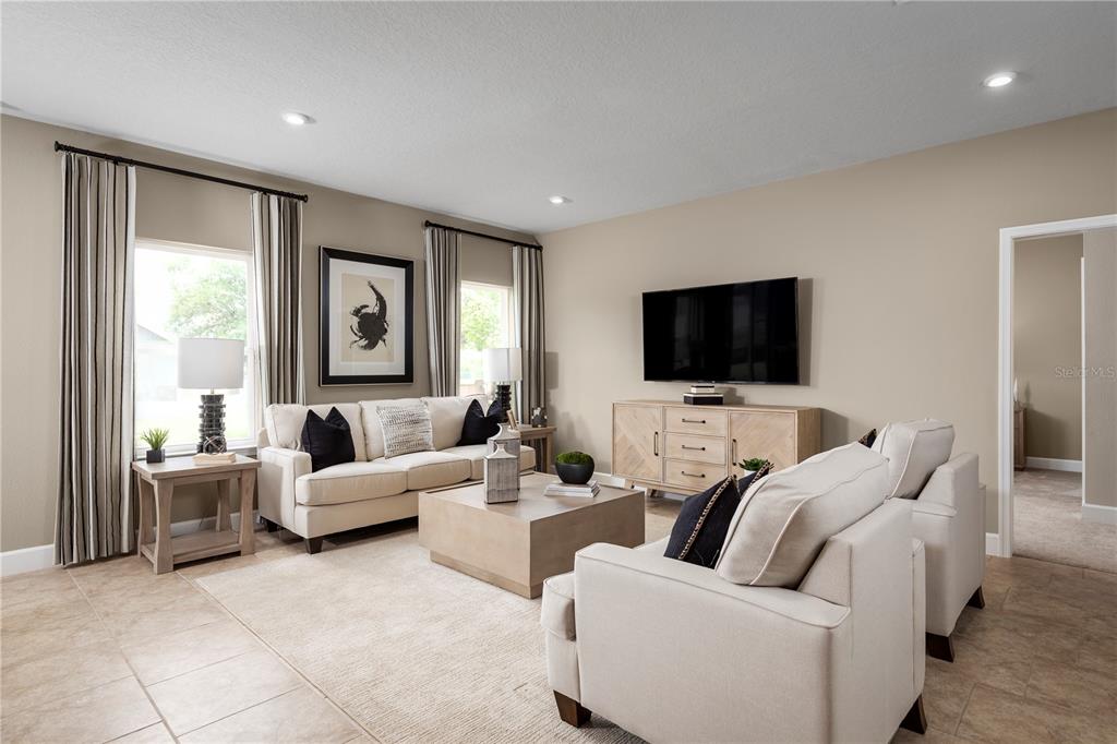 A living room features beige walls, tile flooring, a neutral sofa, and a television console — 291 PRICKLY PEAR COURT, LADY LAKE, FL
