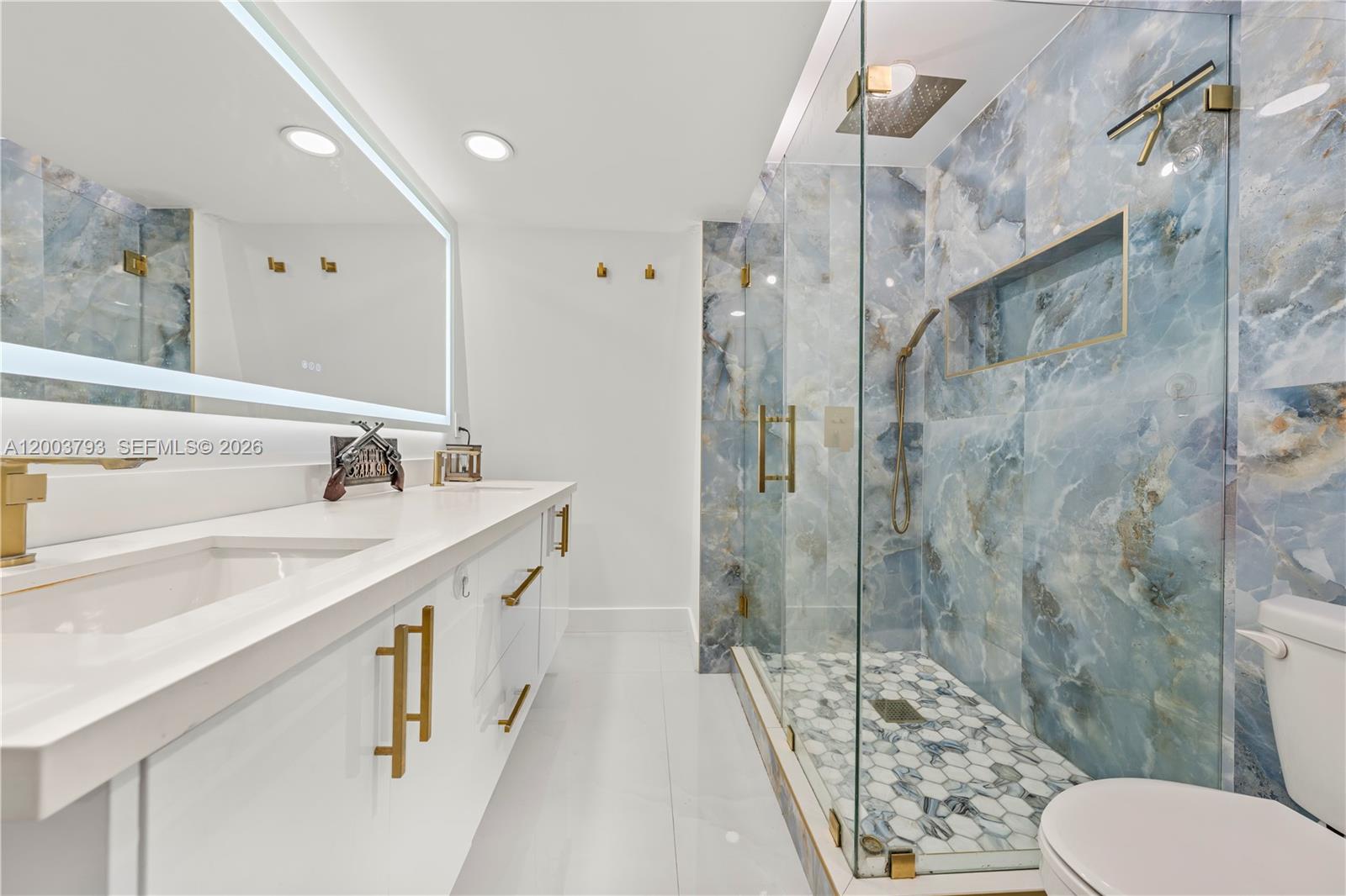 A modern bathroom features a double vanity, a glass-enclosed shower with blue marble-patterned tile — 4089 Forest Hill Dr, Cooper City FL 33026, COOPER CITY, FL