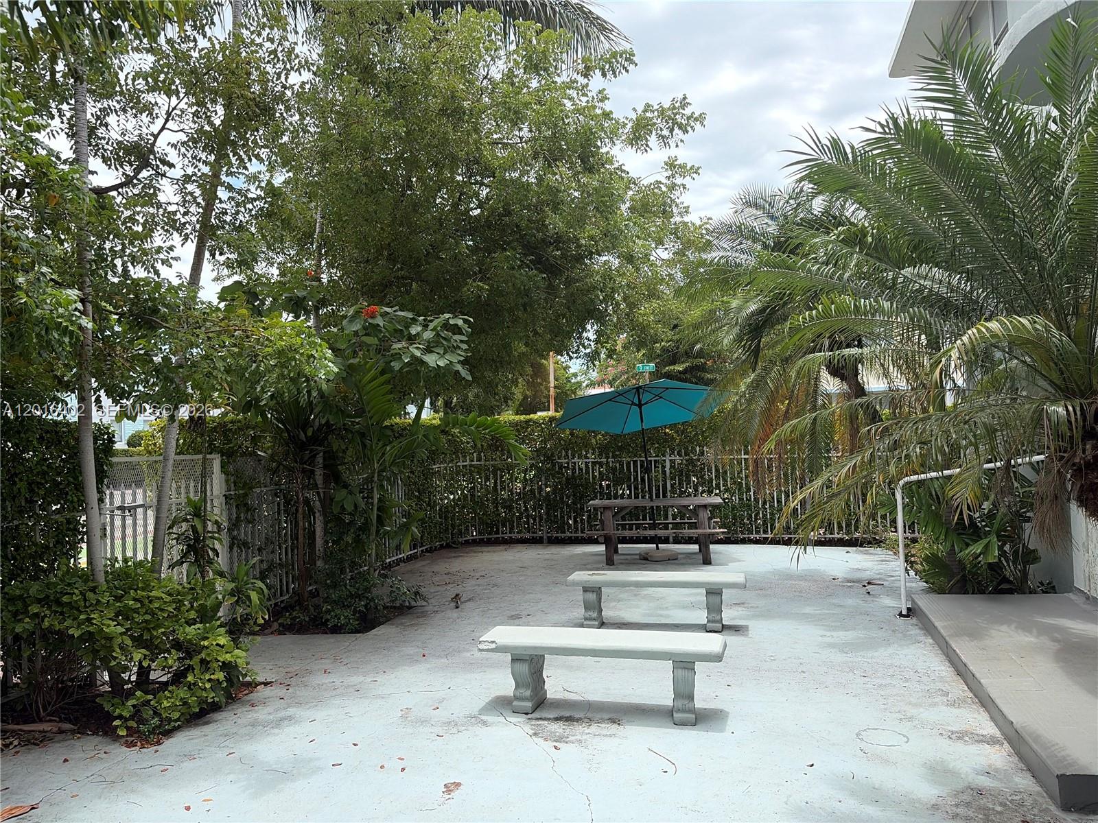 A paved outdoor patio features two stone benches, a picnic table, and a teal umbrella — 900 Jefferson Ave # 2, Miami Beach FL 33139, MIAMI BEACH, FL