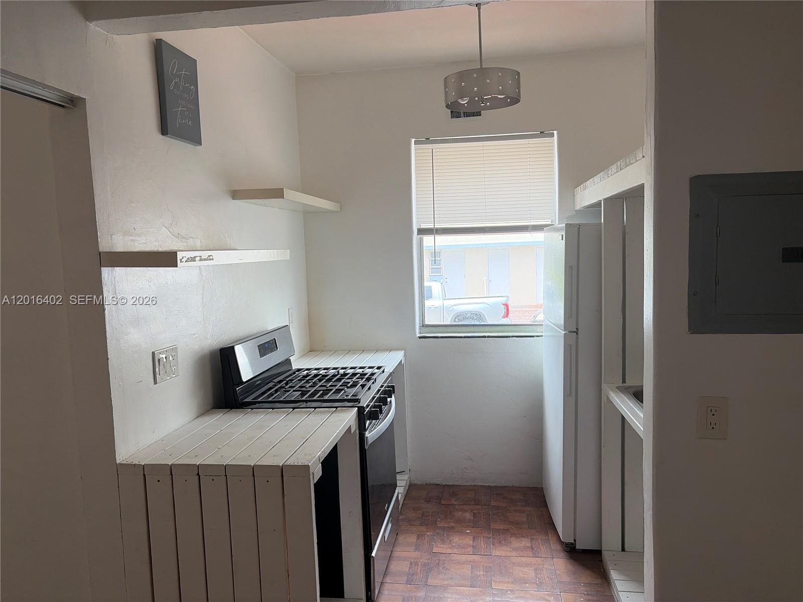 A small kitchen features a gas stove, white wooden counters, a refrigerator, and tiled flooring — 900 Jefferson Ave # 2, Miami Beach FL 33139, MIAMI BEACH, FL