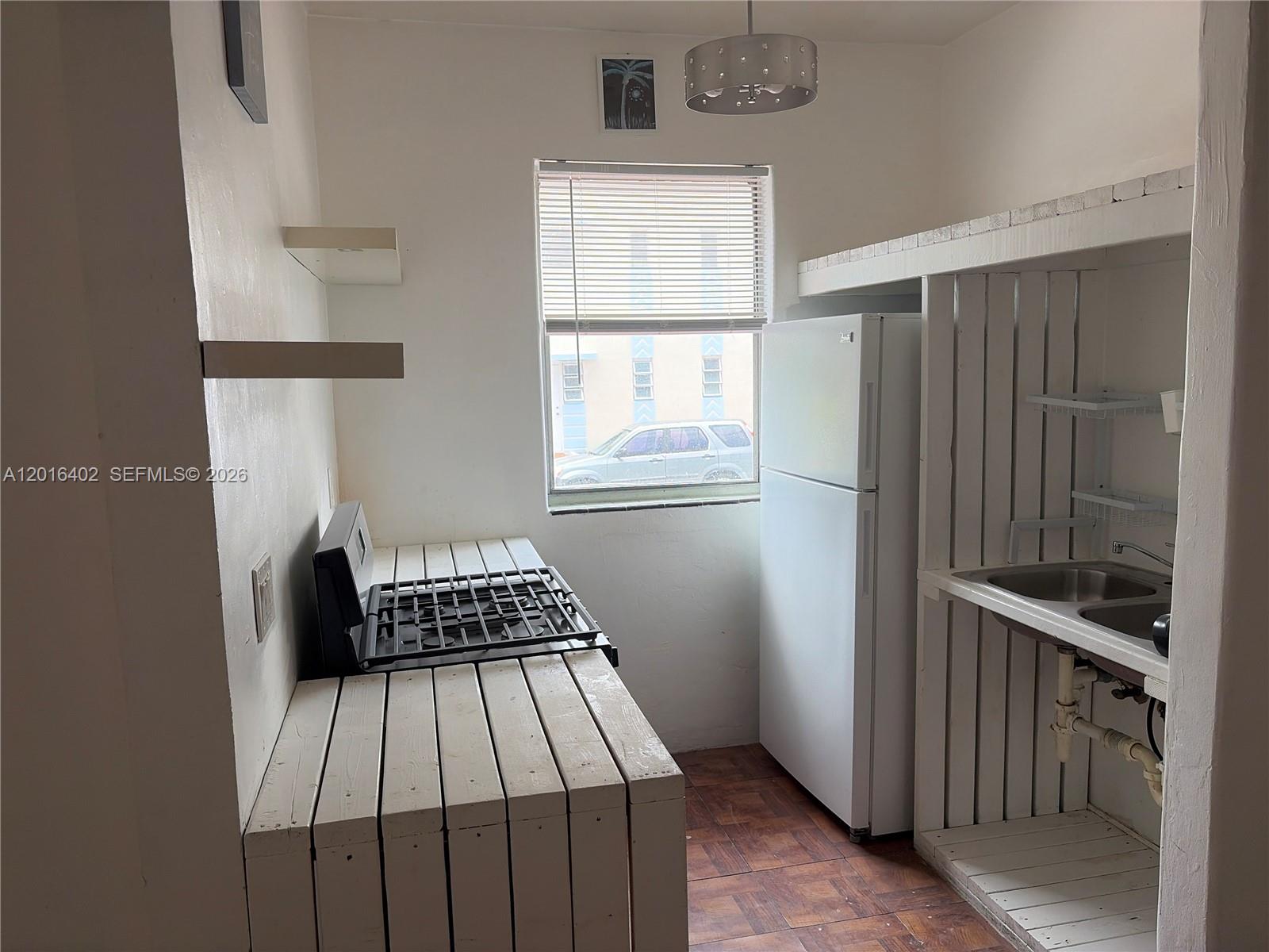 A small kitchen features a white refrigerator, a gas stovetop, and a simple sink area — 900 Jefferson Ave # 2, Miami Beach FL 33139, MIAMI BEACH, FL