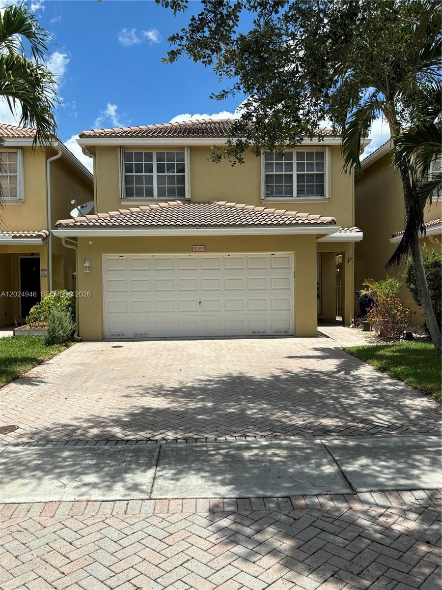 A two-story house with a beige stucco exterior, a white garage door, and a paved driveway — 9283 NW 54th St, Sunrise FL 33351, SUNRISE, FL