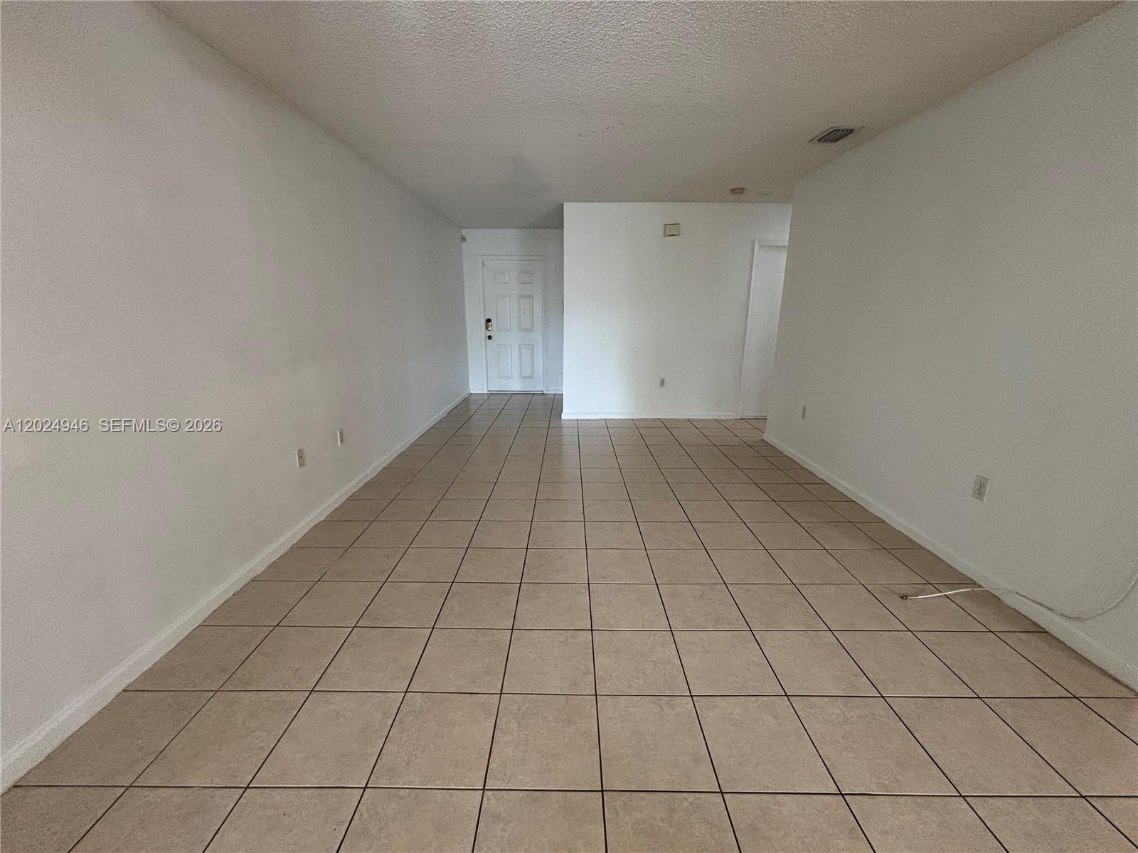 An empty room features white walls, a textured ceiling, and light-colored square floor tiles — 9283 NW 54th St, Sunrise FL 33351, SUNRISE, FL