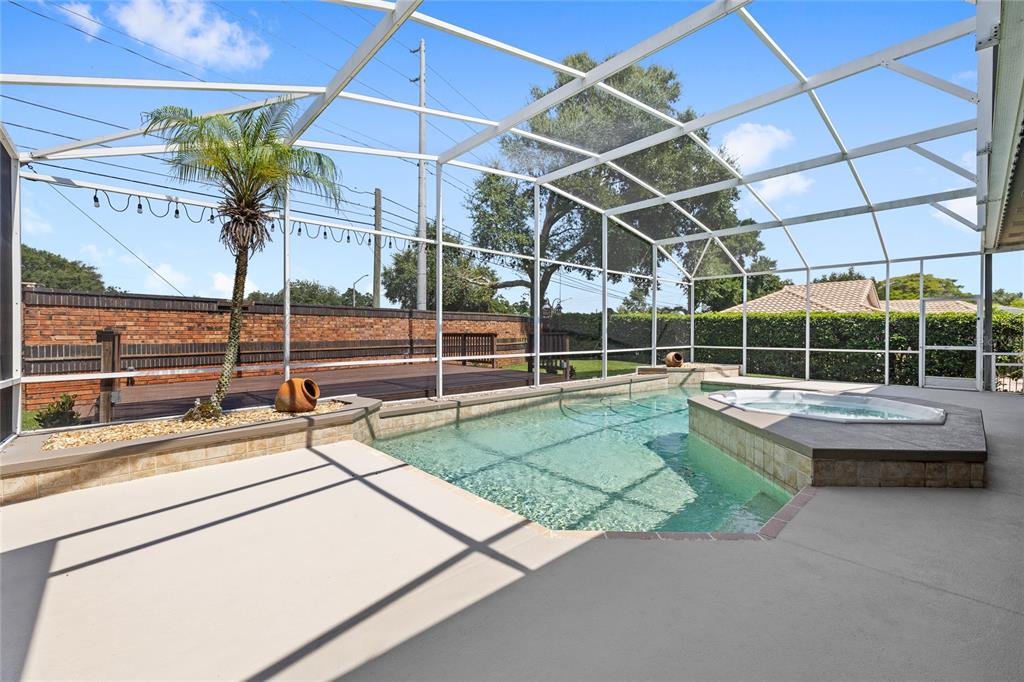 A screened-in pool area features a hot tub, a palm tree, and a wooden deck — 5713 LIBERTY GARDEN COURT, ORLANDO, FL