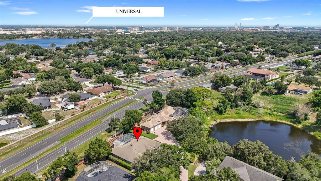 An aerial view shows a residential house with a pool near a lake and road — 5713 LIBERTY GARDEN COURT, ORLANDO, FL