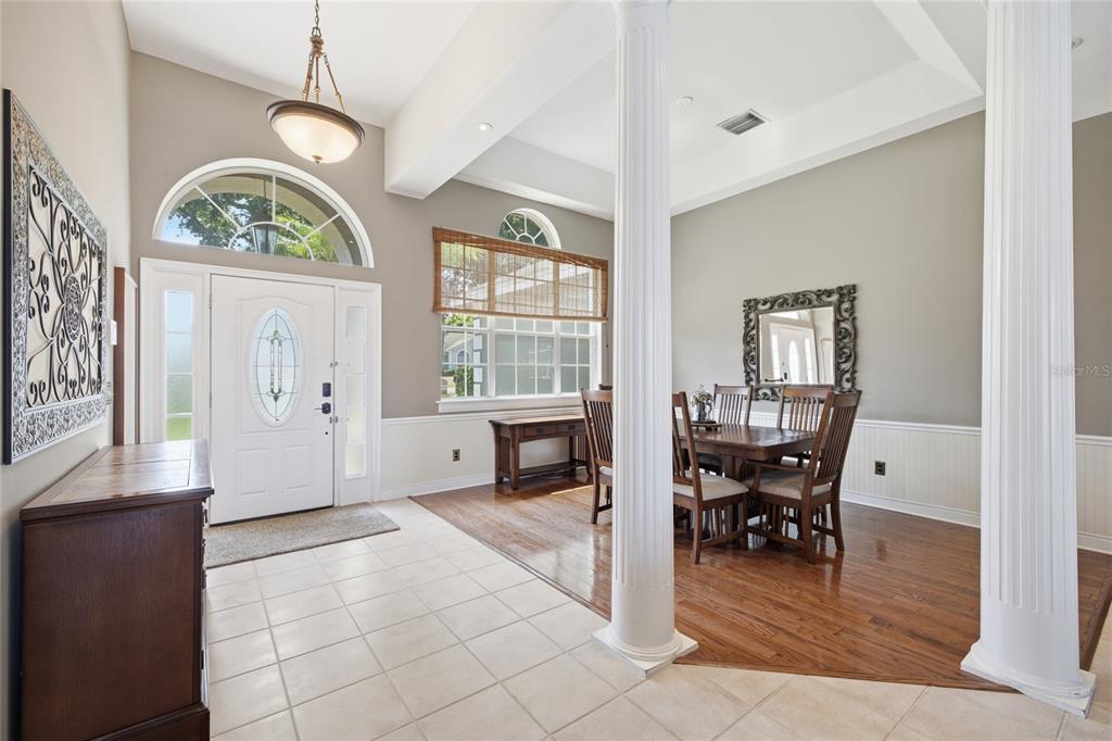 An entryway with tile flooring leads to a dining area with hardwood floors and columns — 5713 LIBERTY GARDEN COURT, ORLANDO, FL
