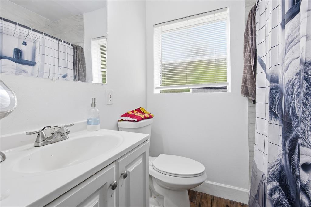A bathroom features a white vanity, a toilet, and a shower with a patterned curtain — 3338 SE 6TH STREET, OCALA, FL