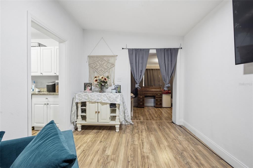 A living area features wood-look flooring, a white console table, and a doorway with curtains — 3338 SE 6TH STREET, OCALA, FL