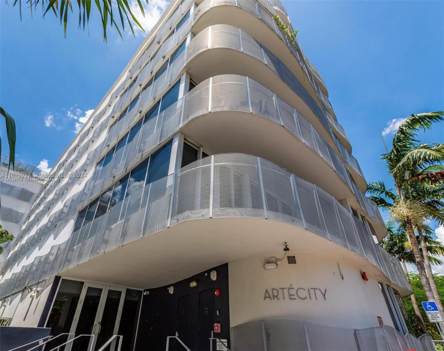 Exterior view of a modern multi-story residential building with curved balconies and metal mesh railings — 2155 Washington Ct # 206, Miami Beach FL 33139, MIAMI BEACH, FL