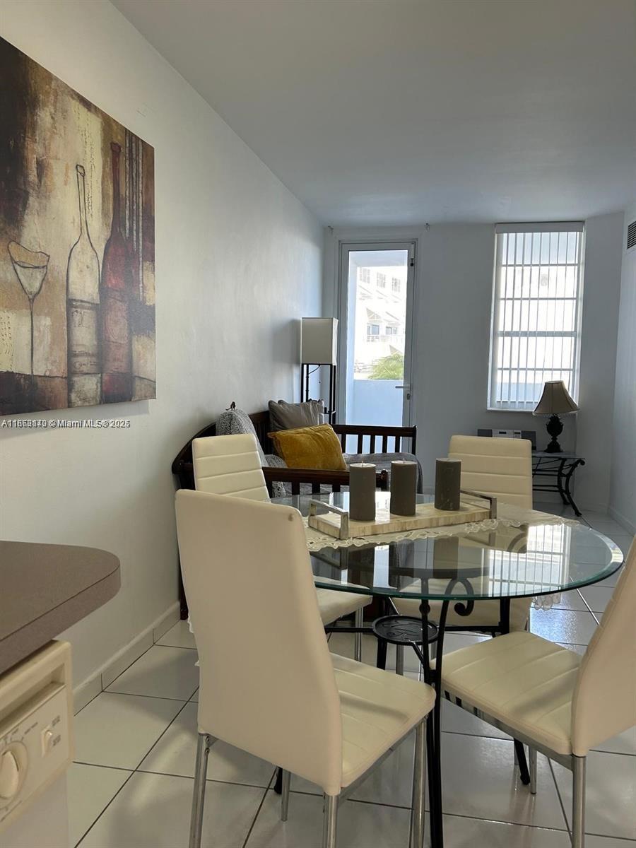 A dining area features a glass-topped table, four white chairs, and a wall-mounted wine painting — 100 Lincoln Rd # 437, Miami Beach FL 33139, MIAMI BEACH, FL