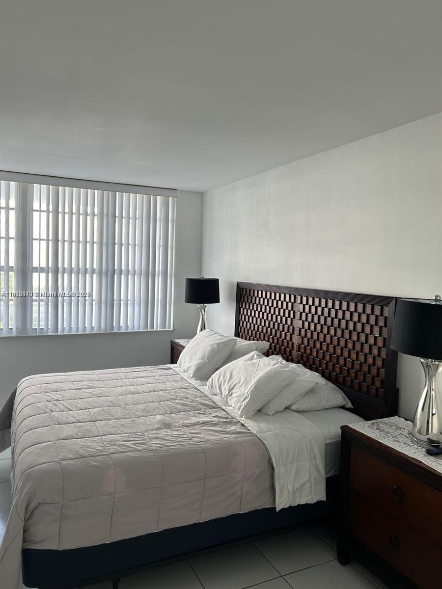 A bedroom features a dark wooden headboard, a bed with white bedding, and two bedside lamps — 100 Lincoln Rd # 437, Miami Beach FL 33139, MIAMI BEACH, FL