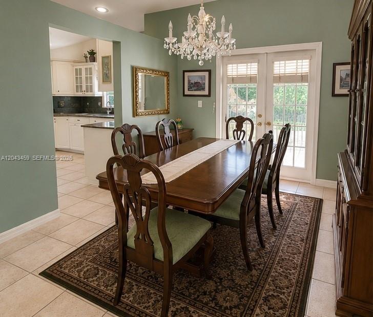 A dining room features a wooden table, chairs with green cushions, and a crystal chandelier — 9812 SW 77th Pl, Miami FL 33156, MIAMI, FL