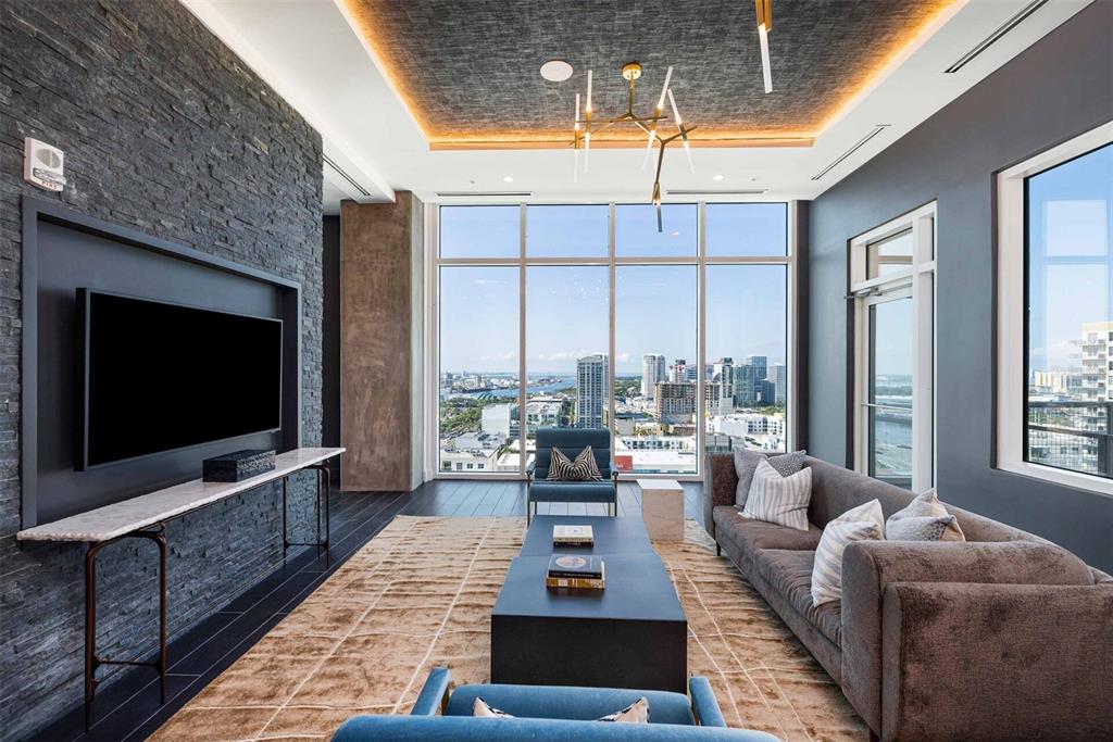 A modern living room features a stone accent wall, floor-to-ceiling windows, and a city view — 601 N 12TH STREET N UNIT A2, TAMPA, FL