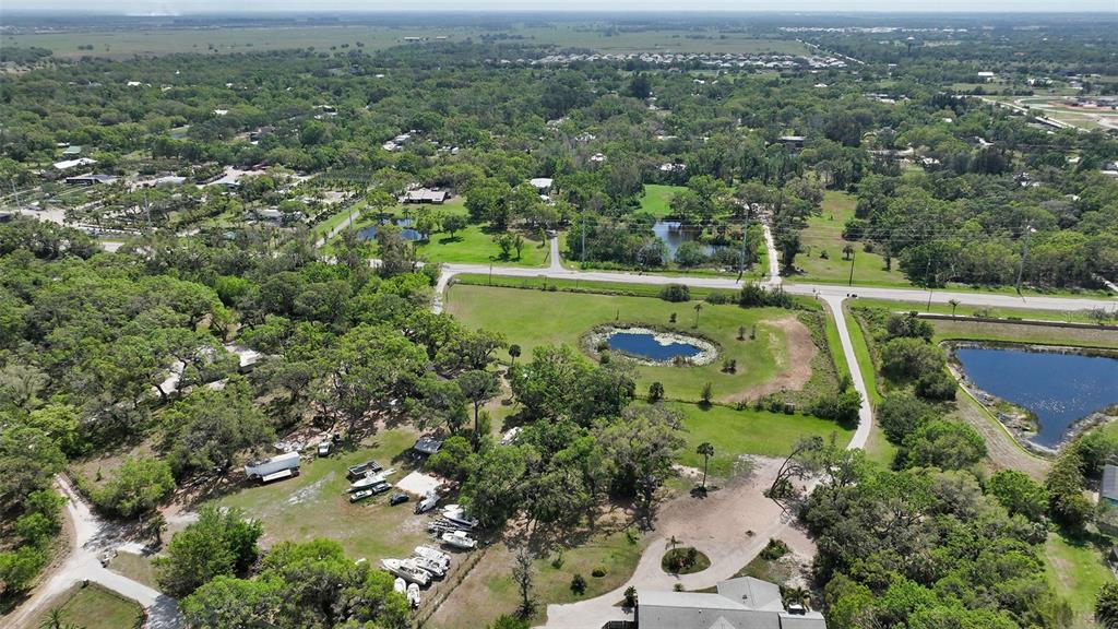 An aerial view shows a rural property with a house, several ponds, and parked boats — 7025 CLARK ROAD, SARASOTA, FL