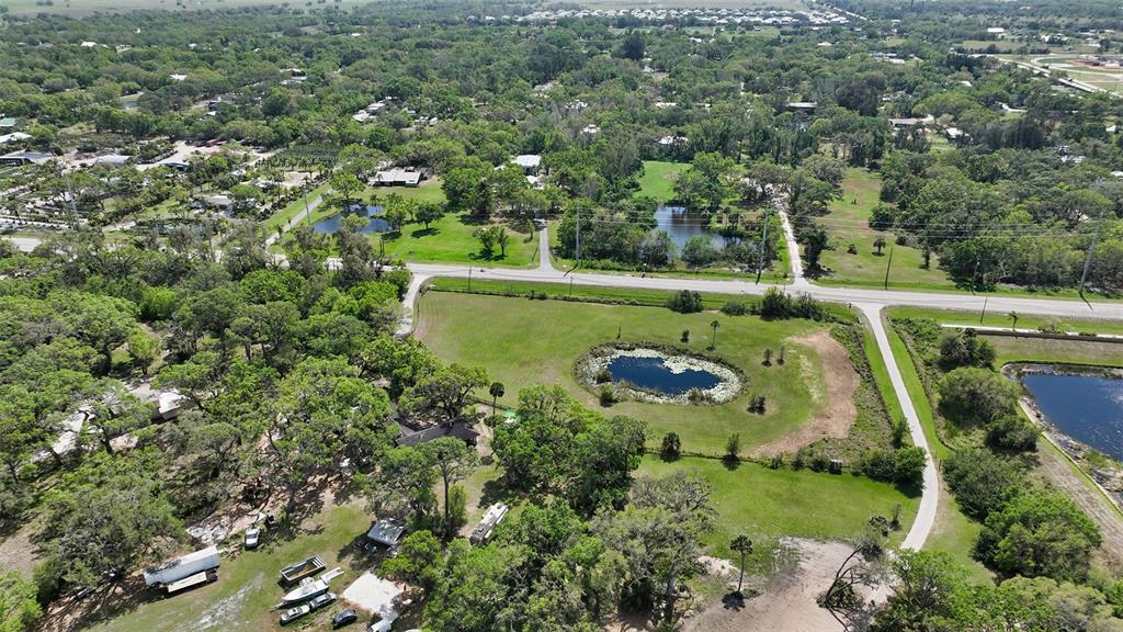 An aerial view shows a rural property with a pond, trees, and several outbuildings — 7025 CLARK ROAD, SARASOTA, FL