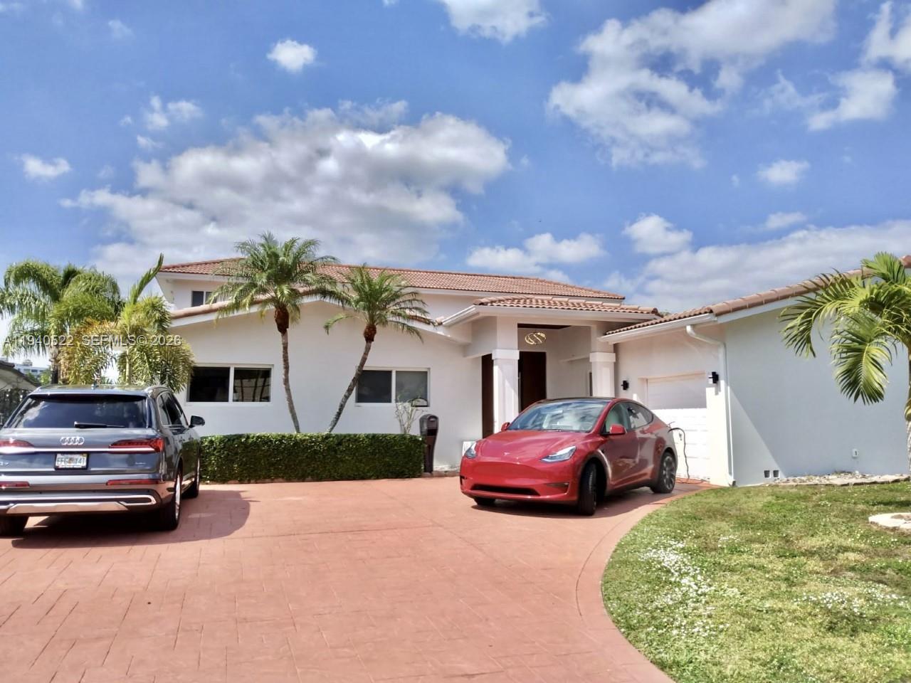 A white two-story house with a red-tiled roof, a paved driveway, and two parked cars — 13240 Ortega Ln, North Miami FL 33181, NORTH MIAMI, FL