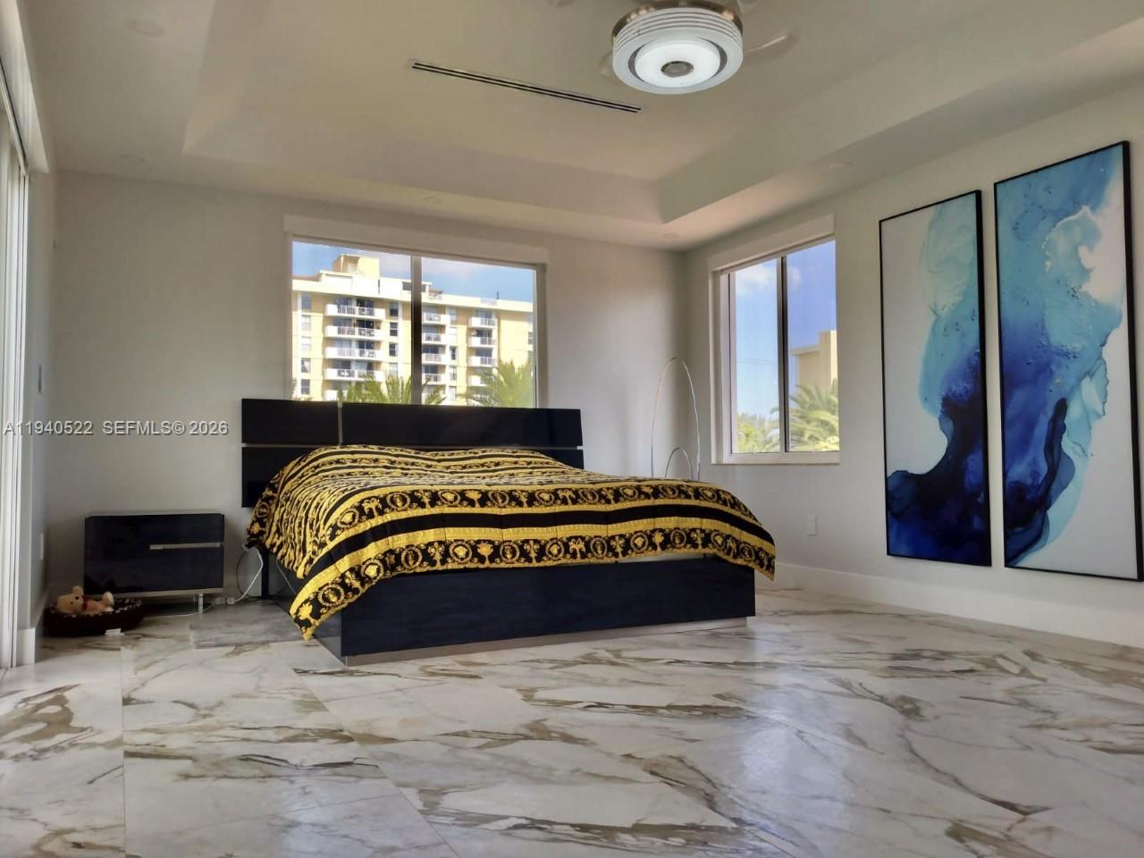 A bedroom features a bed with a patterned cover, marble flooring, and two large abstract paintings — 13240 Ortega Ln, North Miami FL 33181, NORTH MIAMI, FL