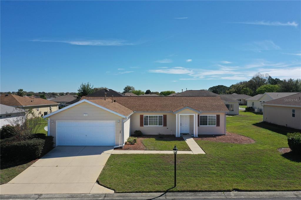 A single-story, tan-sided house with a two-car garage and a brown shingled roof — 13828 SE 85TH CIRCLE, SUMMERFIELD, FL