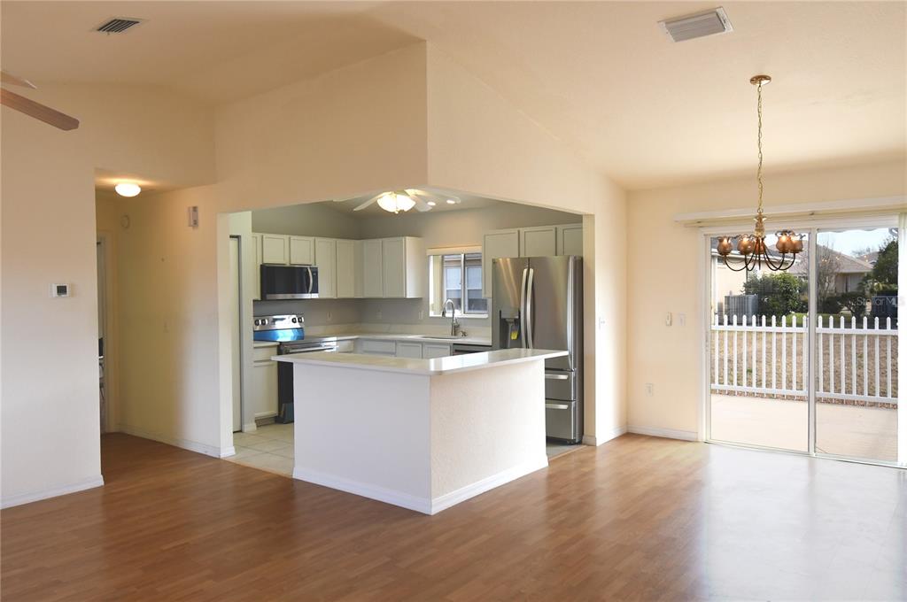 A kitchen with white cabinets and stainless steel appliances opens to a dining area — 13828 SE 85TH CIRCLE, SUMMERFIELD, FL