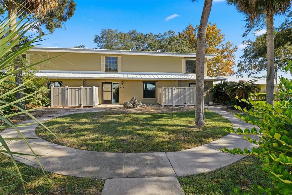 A two-story tan townhouse with a white metal roof and a curved concrete walkway — 11328 W BAYSHORE DRIVE, CRYSTAL RIVER, FL