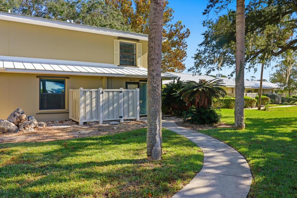 A tan two-story building with a white metal roof, privacy fence, and curved concrete walkway — 11328 W BAYSHORE DRIVE, CRYSTAL RIVER, FL