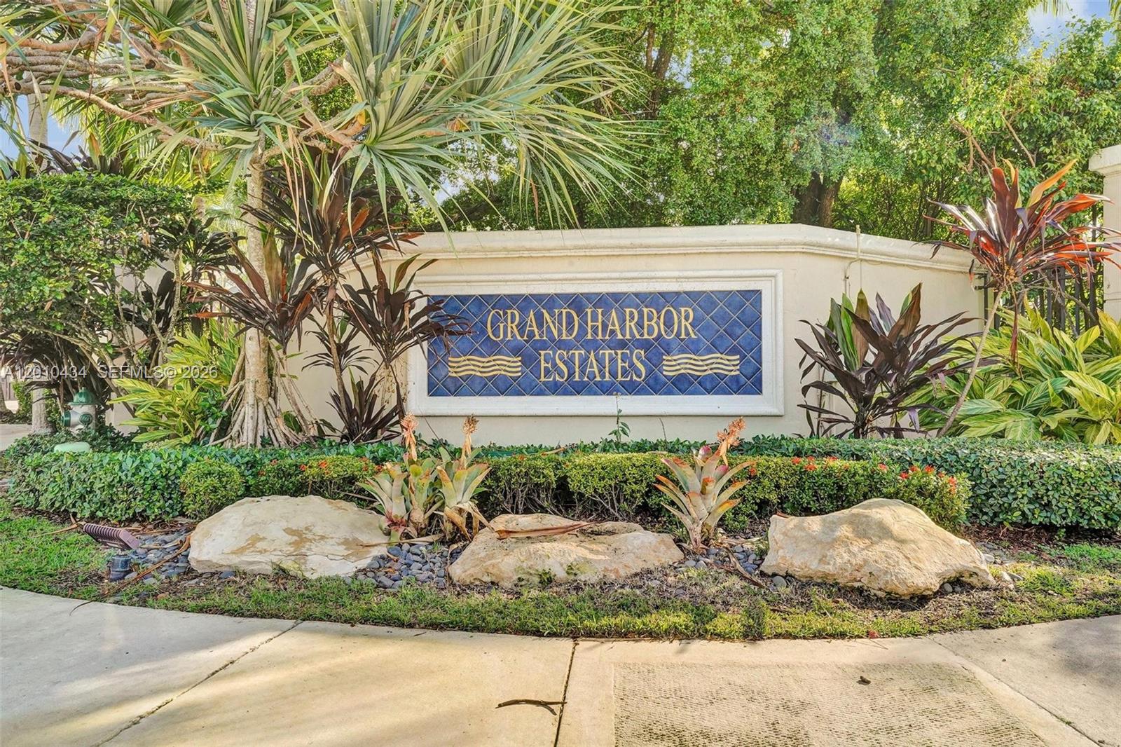 A stone entrance sign for Grand Harbor Estates is surrounded by lush tropical landscaping — 1575 Windjammer Way, Hollywood FL 33019, HOLLYWOOD, FL