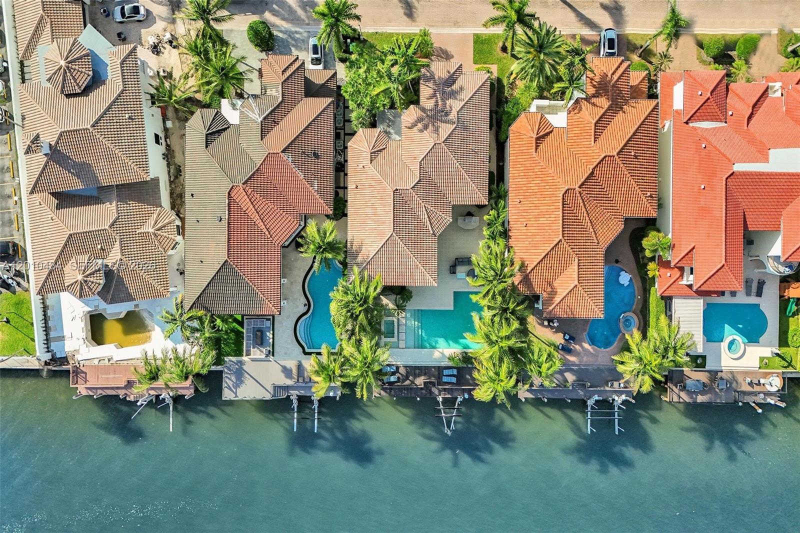 An aerial view shows four waterfront houses with swimming pools and private docks along a canal — 1575 Windjammer Way, Hollywood FL 33019, HOLLYWOOD, FL