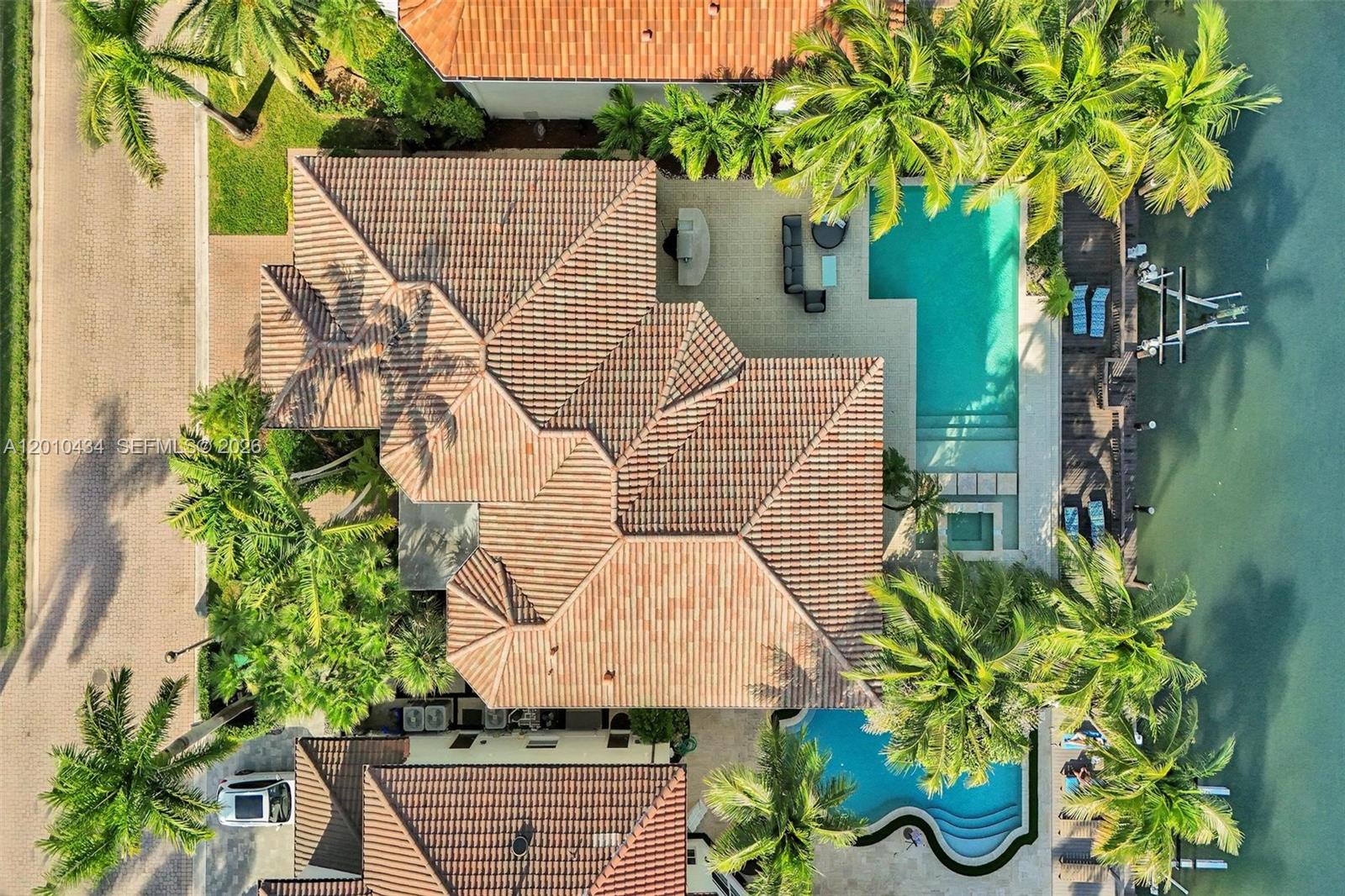 An aerial view shows a house with a tiled roof, two swimming pools, and palm trees — 1575 Windjammer Way, Hollywood FL 33019, HOLLYWOOD, FL