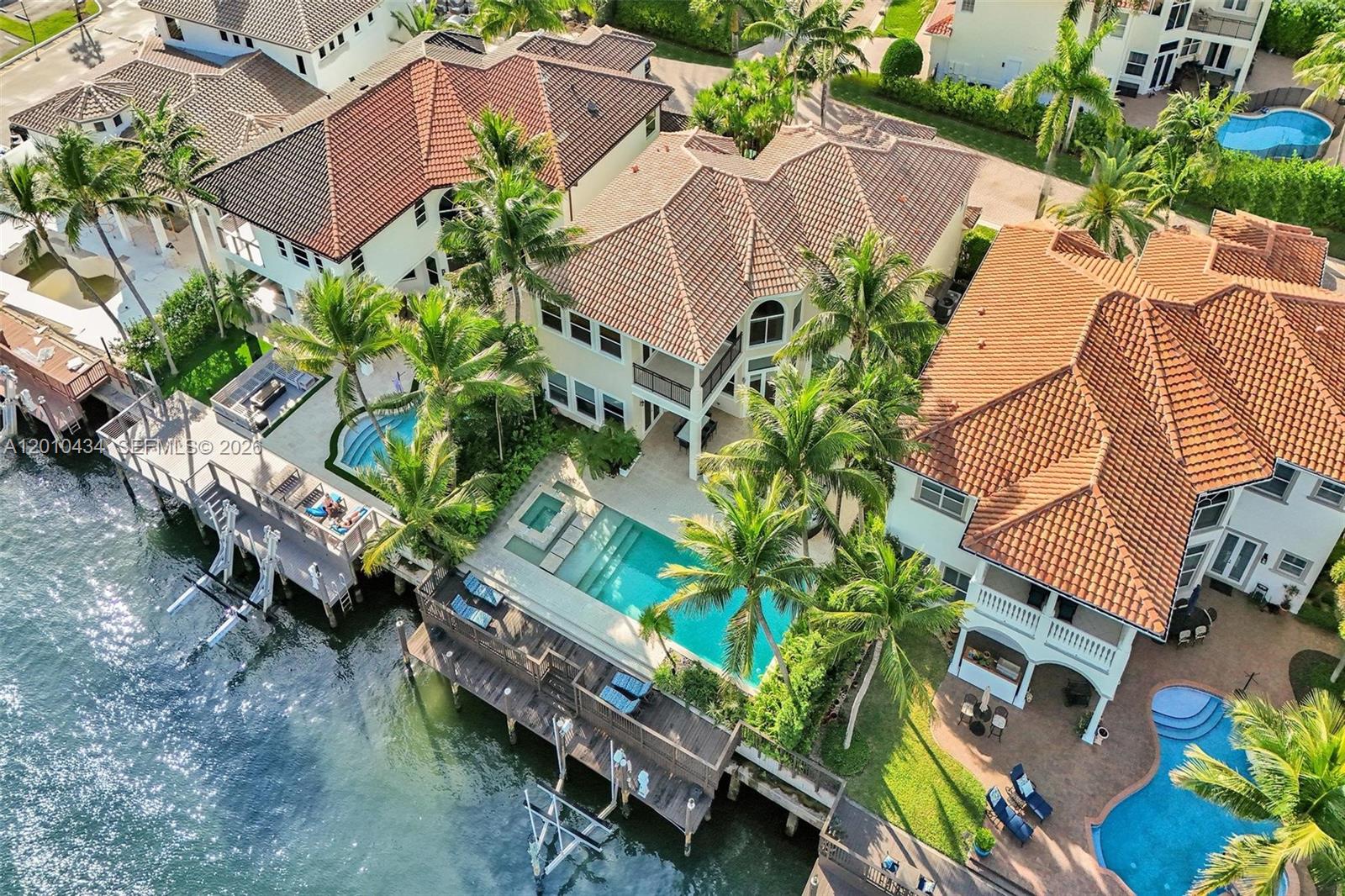 An aerial view shows three waterfront homes with tiled roofs, swimming pools, and private docks — 1575 Windjammer Way, Hollywood FL 33019, HOLLYWOOD, FL