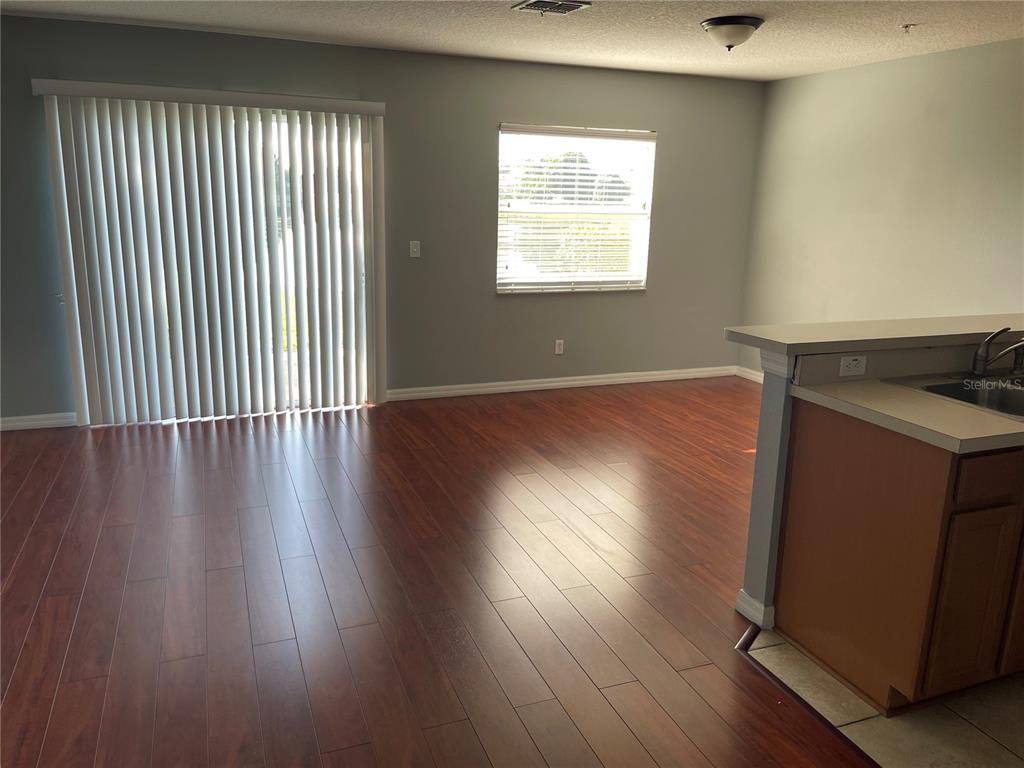A living room with wood-look flooring, a sliding glass door, and a kitchen breakfast bar — 13433 STARRY NIGHT COURT UNIT 11, ORLANDO, FL