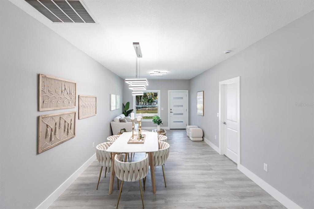 A dining area with a modern chandelier, white table, and chairs on light wood flooring — 1024 SENTINELA BOULEVARD, LEHIGH ACRES, FL