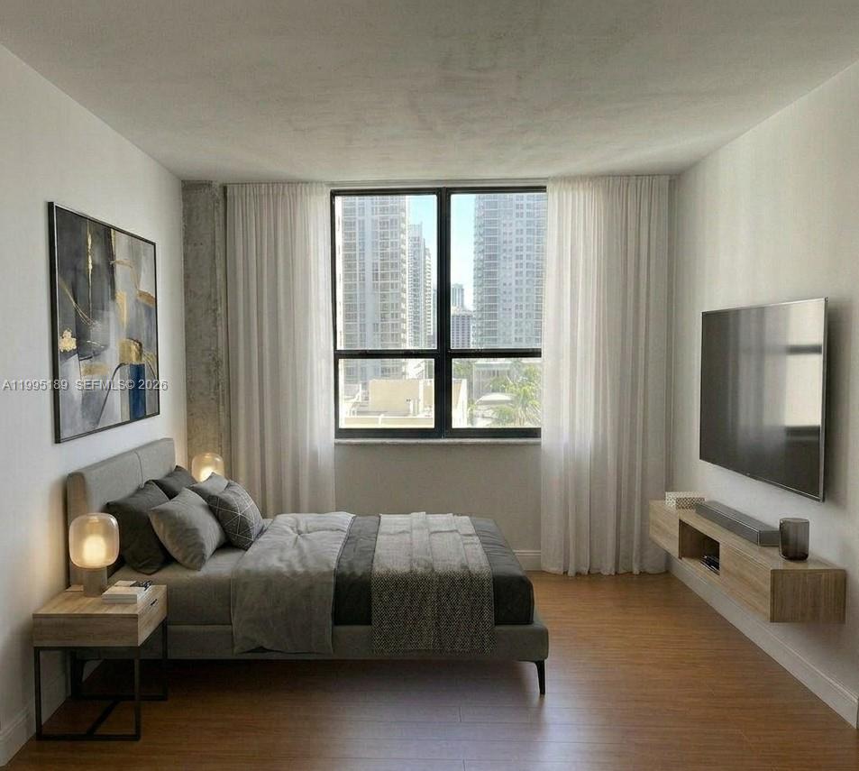 A modern bedroom features a bed, wall-mounted television, floating console, and city skyline views — 10185 Collins Ave # 308, Bal Harbour FL 33154, BAL HARBOUR, FL