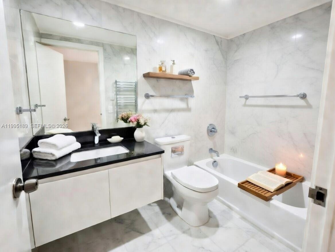 A bathroom features a white vanity with a black countertop, a toilet, and a bathtub — 10185 Collins Ave # 308, Bal Harbour FL 33154, BAL HARBOUR, FL