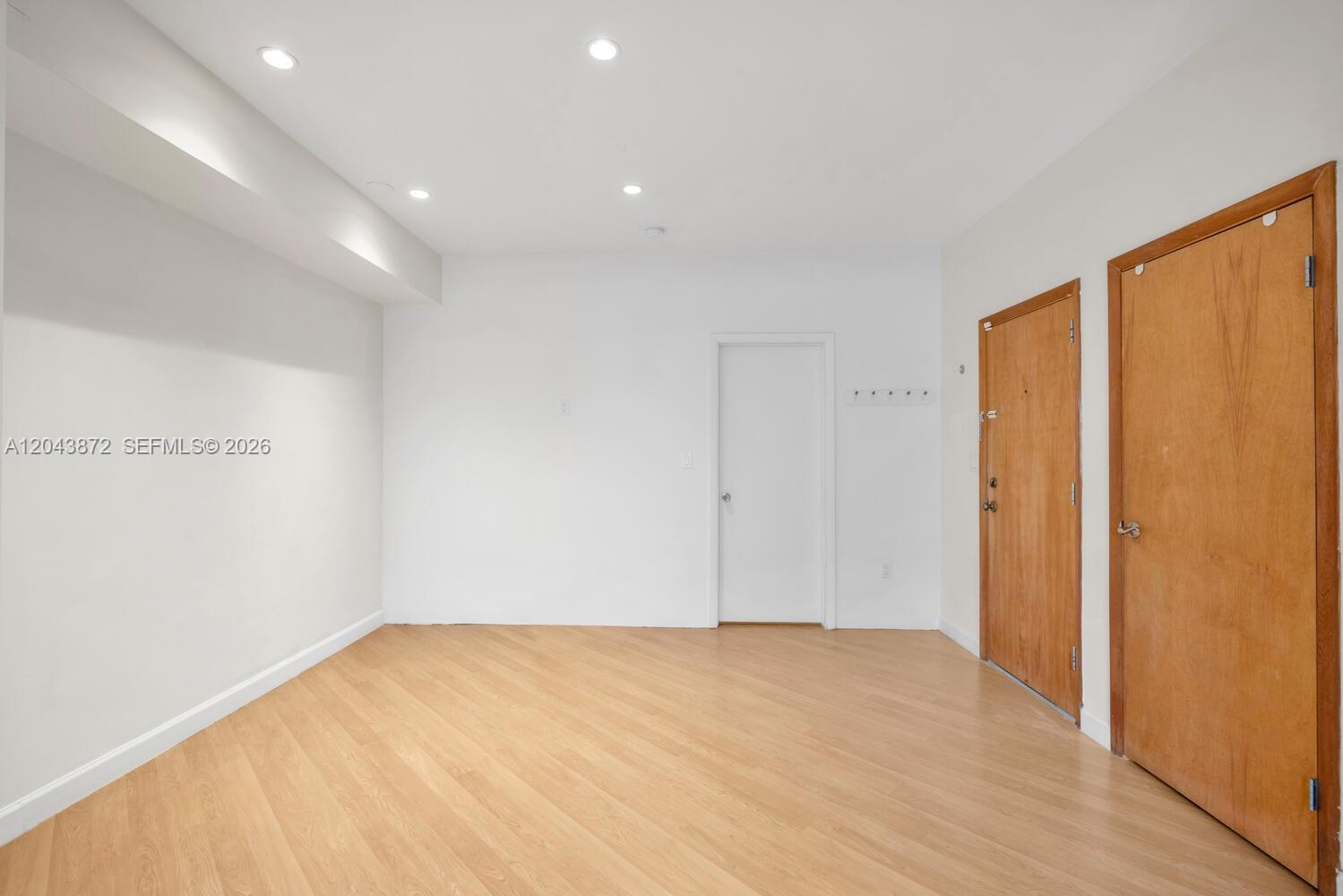 A room with light wood-look flooring, white walls, recessed lighting, and two wooden doors — 305 Jefferson Ave # 2, Miami Beach FL 33139, MIAMI BEACH, FL
