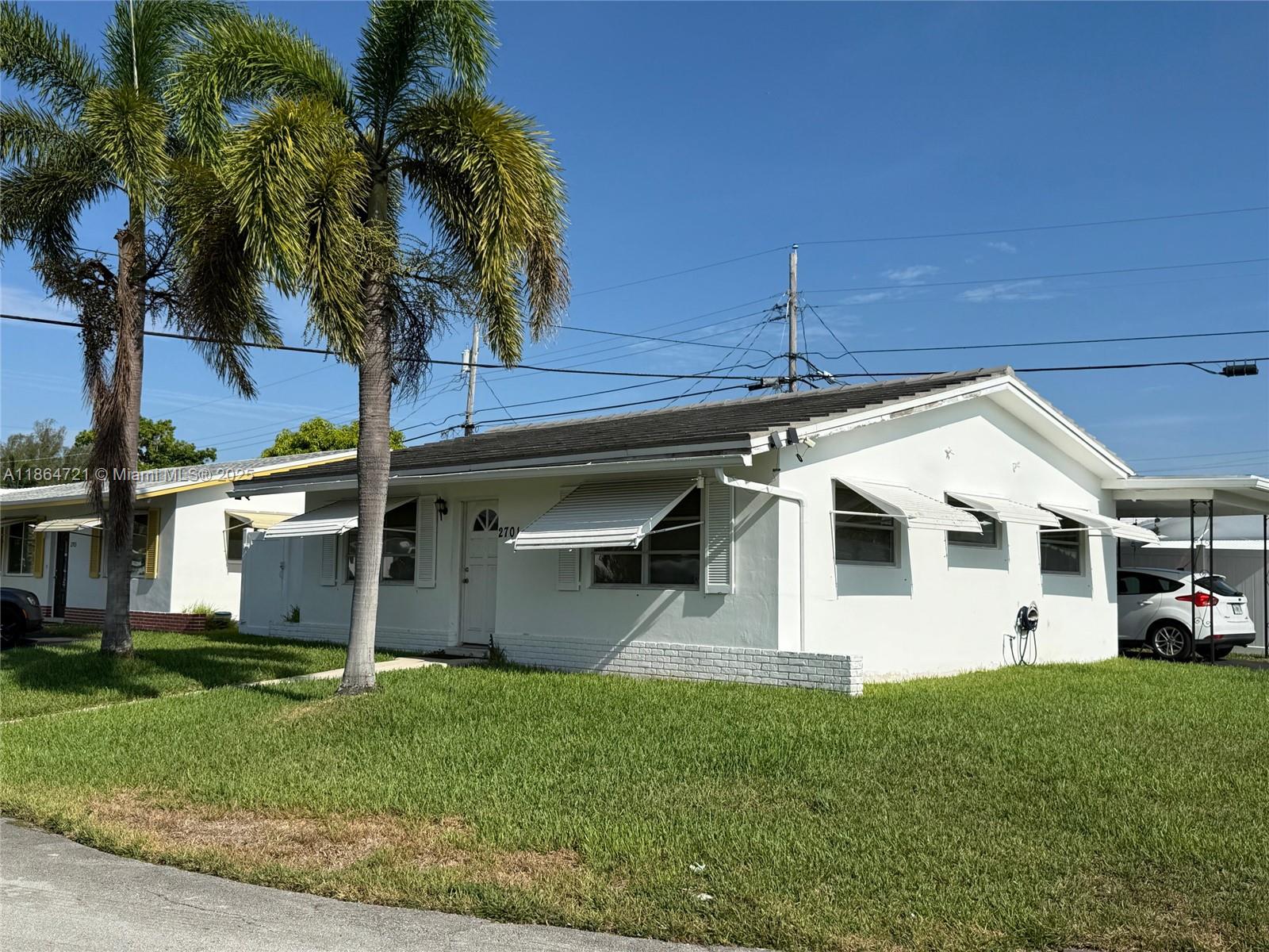 A white single-story house with metal awnings and a palm tree in the front yard — 2701 NW 52nd Ct, Tamarac FL 33309, TAMARAC, FL
