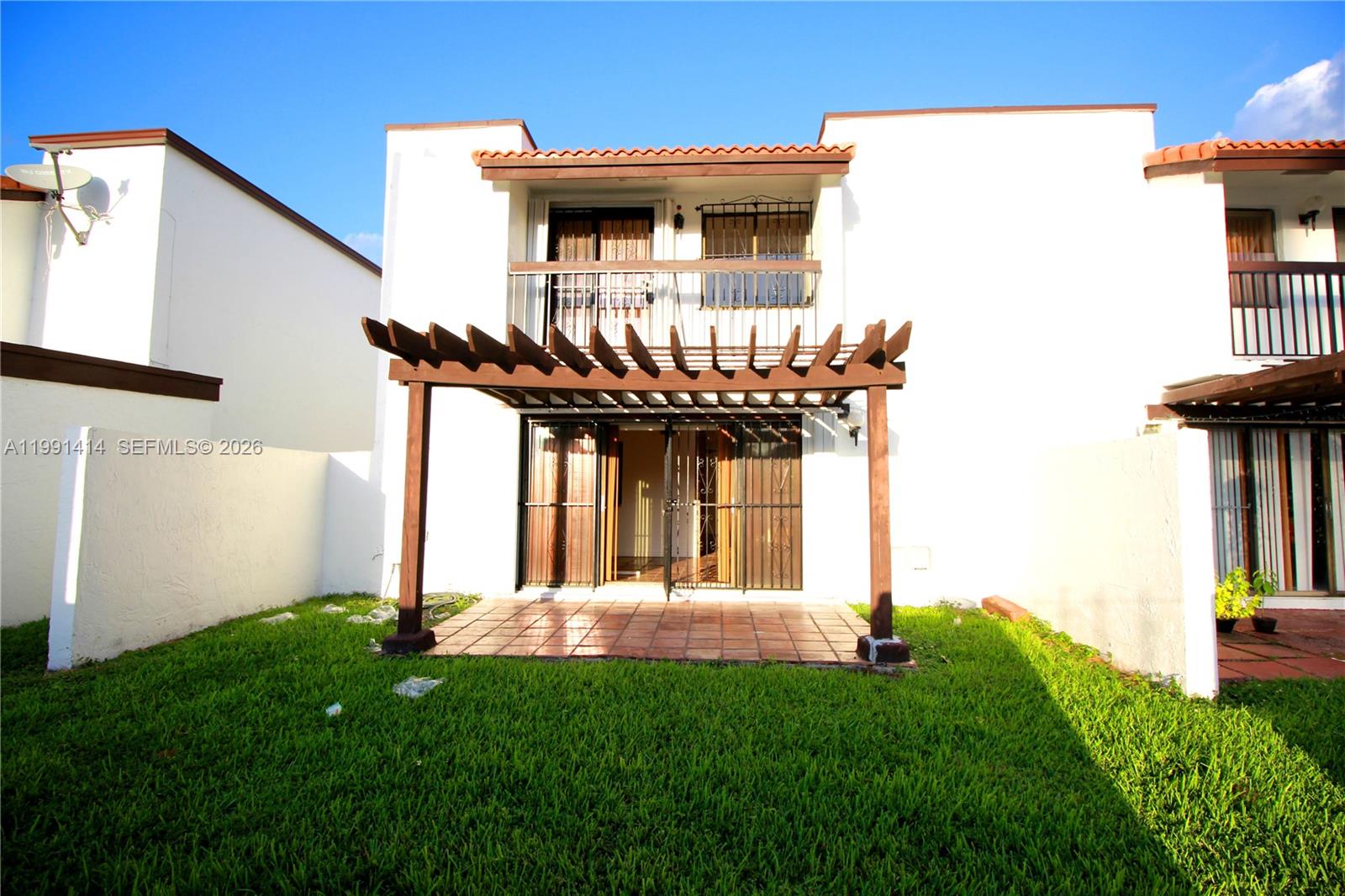 A two-story white townhouse features a wooden pergola over a tiled patio and balcony — 1221 SW 124th Ct, Miami FL 33184, MIAMI, FL