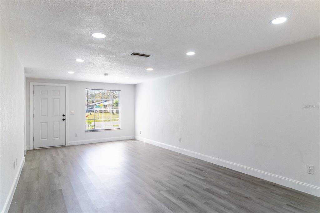 An empty room with light gray walls, recessed lighting, and wood-look flooring — 3432 DANNY BRYAN BOULEVARD, TAMPA, FL