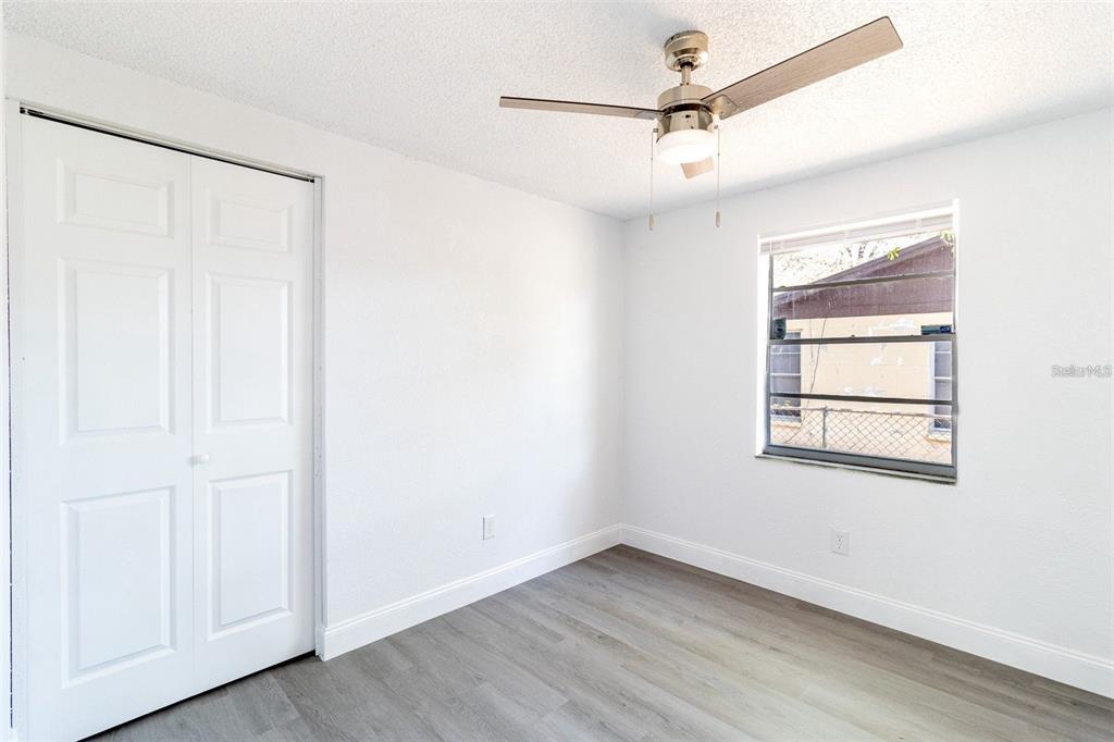 A bedroom with white walls, gray wood-look flooring, a ceiling fan, and a closet — 3432 DANNY BRYAN BOULEVARD, TAMPA, FL