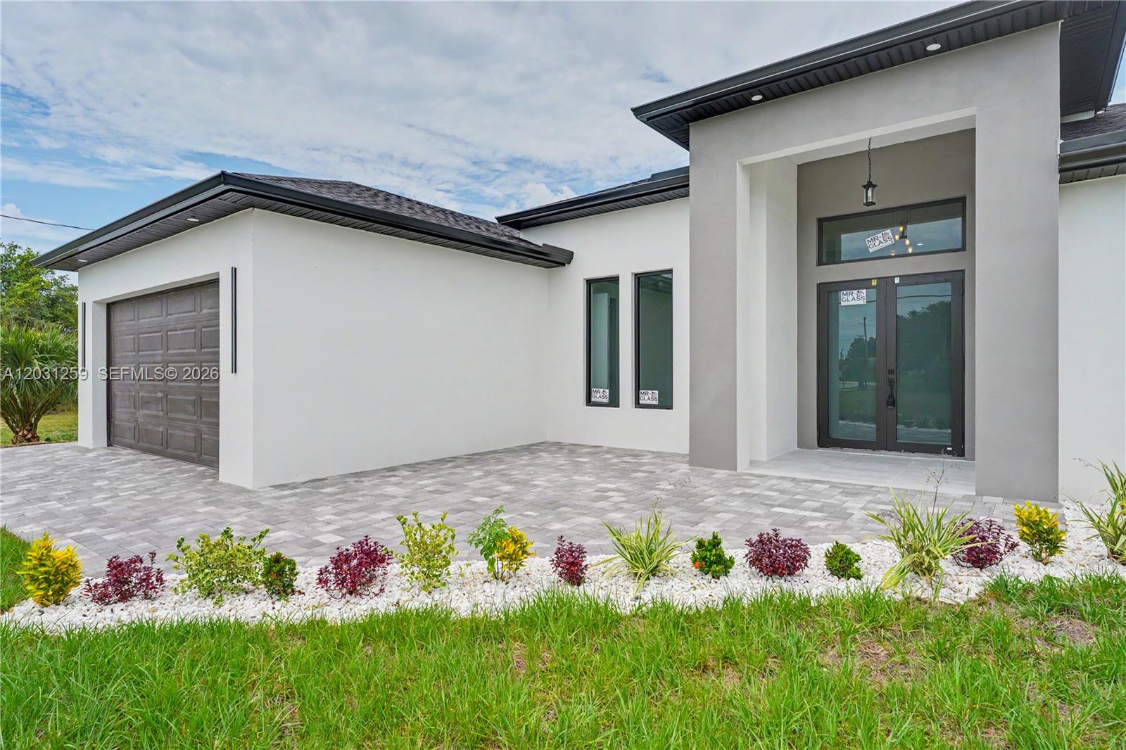 The exterior of a modern house features a paved driveway, a garage, and a glass entryway — 3500 NE 17th pl, Cape Coral FL 33909, CAPE CORAL, FL