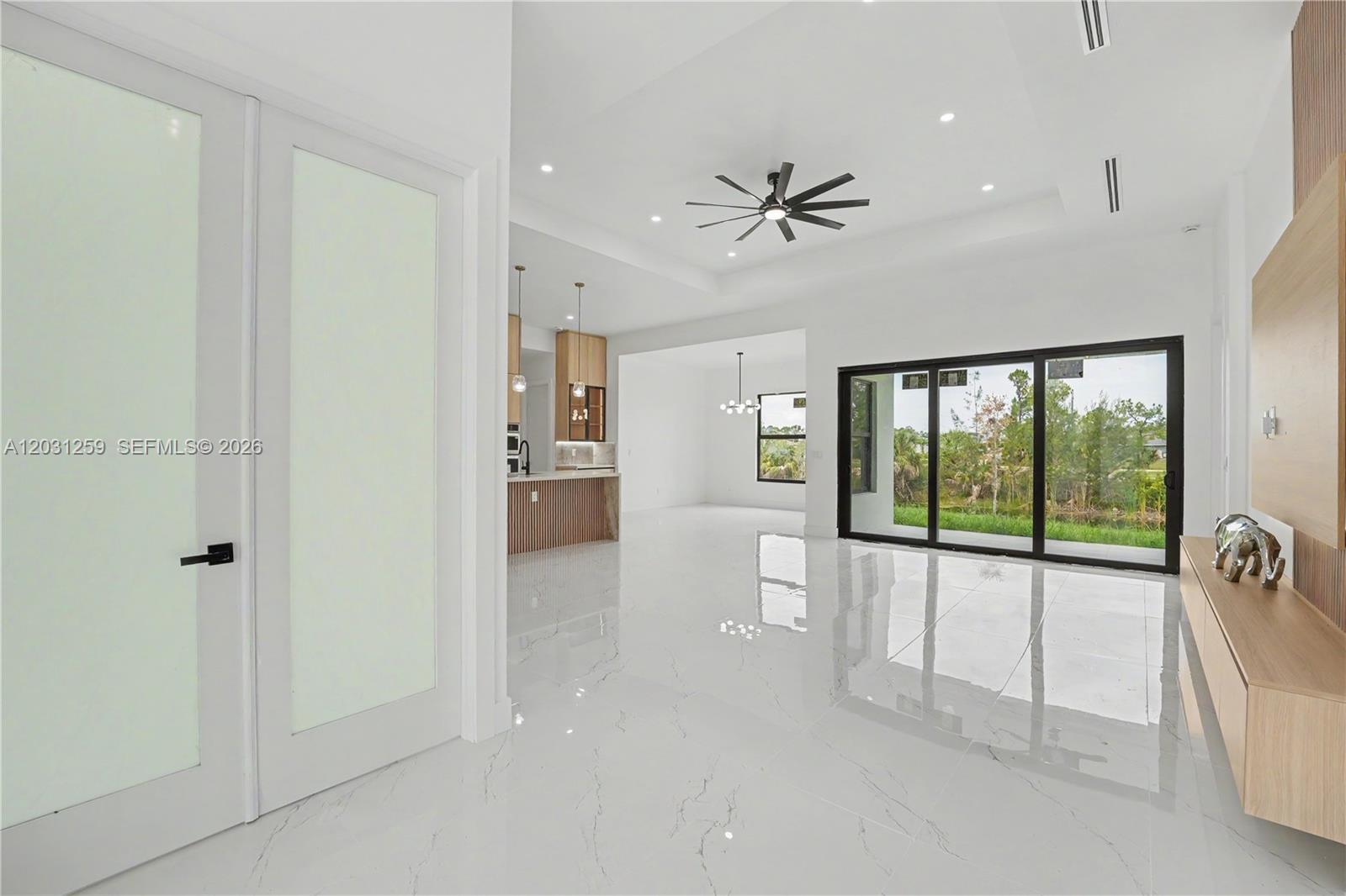 A bright living area features white marble floors, a tray ceiling, and large sliding doors — 3500 NE 17th pl, Cape Coral FL 33909, CAPE CORAL, FL
