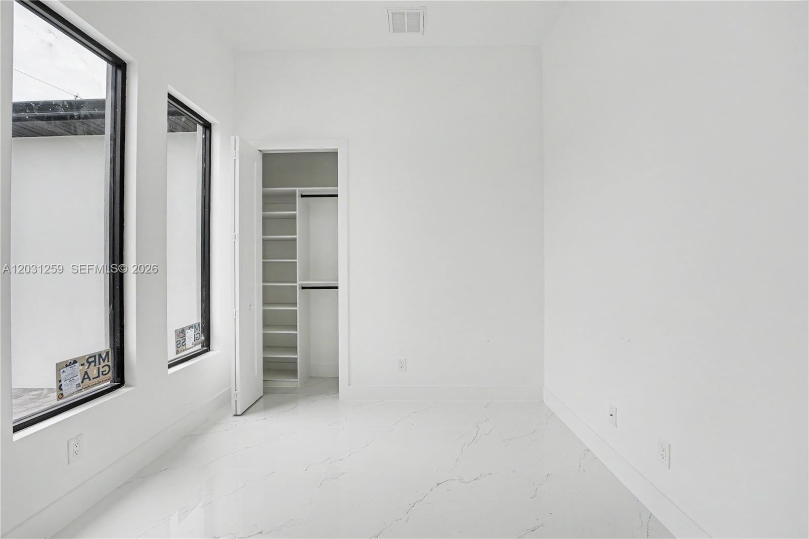 A minimalist room features white walls, marble-look tile flooring, two large windows, and a closet — 3500 NE 17th pl, Cape Coral FL 33909, CAPE CORAL, FL