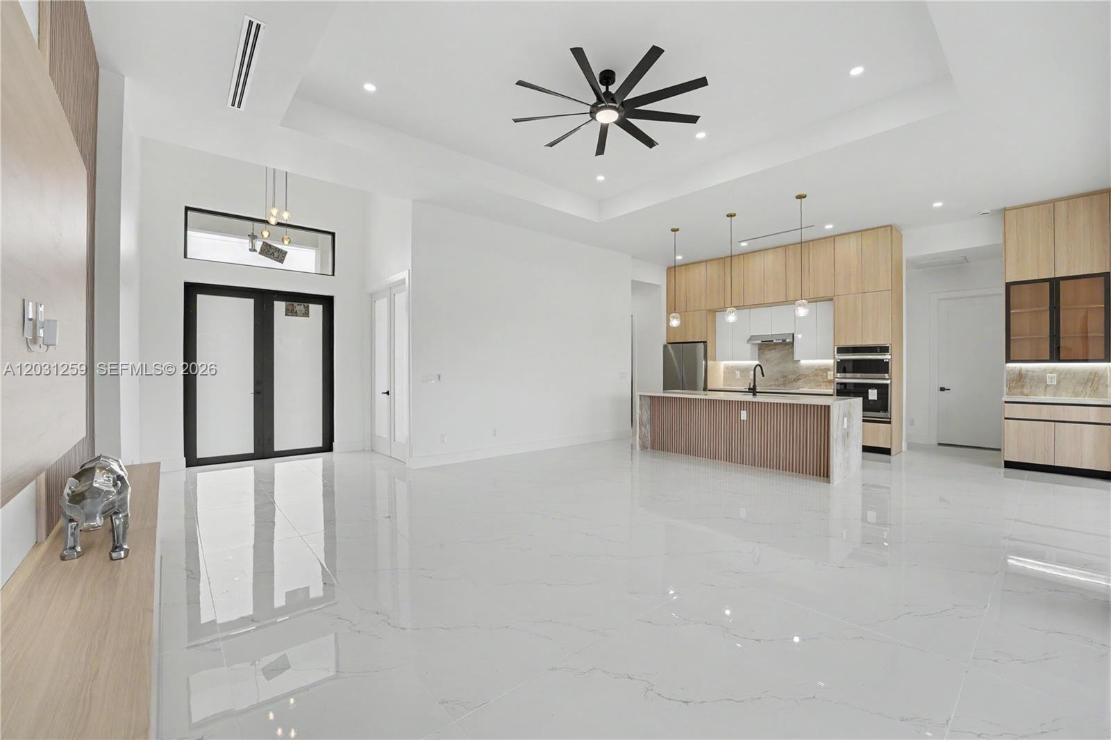 A modern open-concept kitchen and living area features white tile floors and wood cabinetry — 3500 NE 17th pl, Cape Coral FL 33909, CAPE CORAL, FL