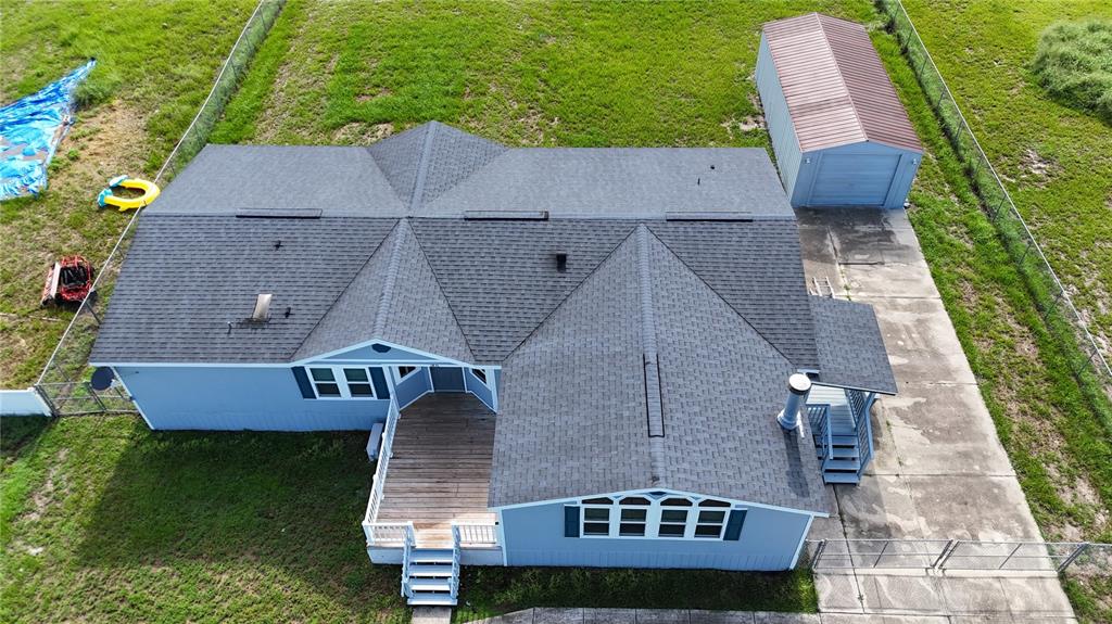 An aerial view shows a blue house with a shingled roof, deck, and detached garage — 1831 WINCHESTER COURT S, ST CLOUD, FL