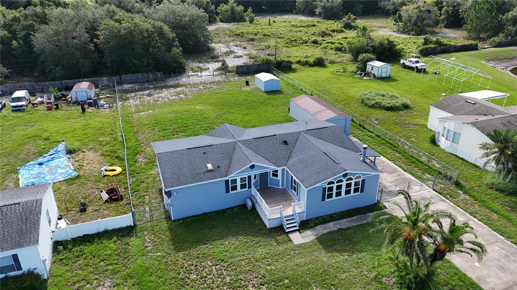 An aerial view shows a blue house with a gray roof and a wooden deck — 1831 WINCHESTER COURT S, ST CLOUD, FL