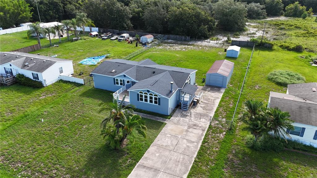 An aerial view shows a blue house with a dark roof, a driveway, and outbuildings — 1831 WINCHESTER COURT S, ST CLOUD, FL