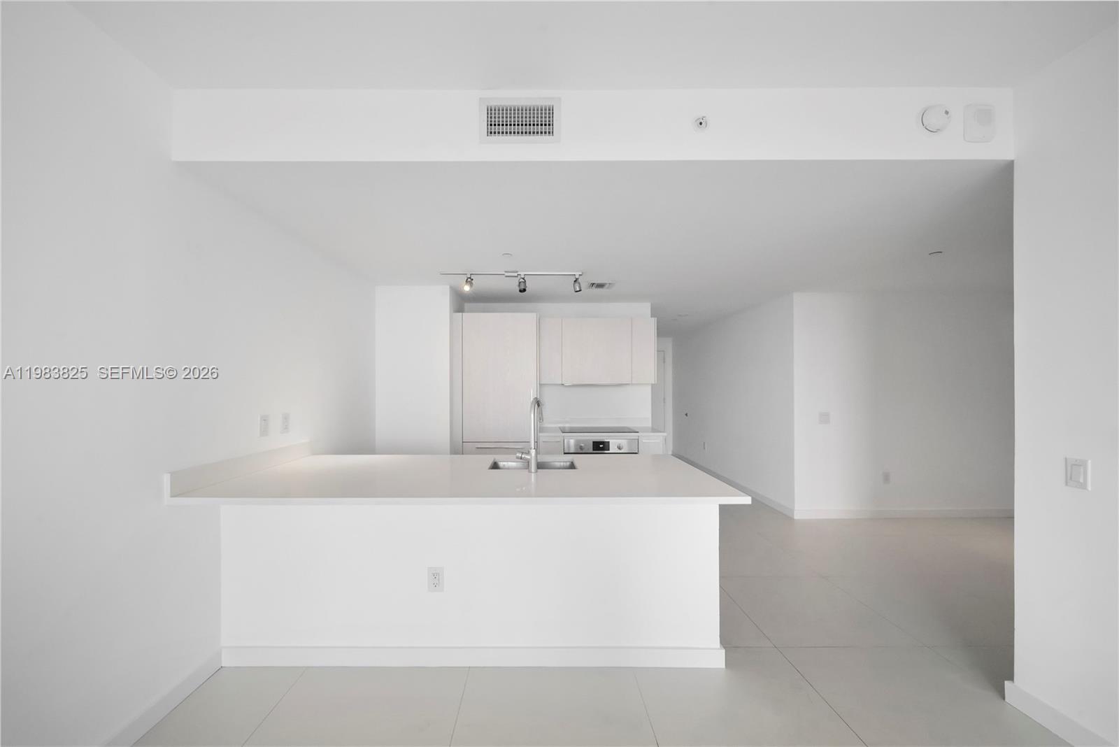 A minimalist kitchen features white cabinetry, a quartz island, and light tile flooring — 501 NE 31st St # 3110, Miami FL 33137, MIAMI, FL