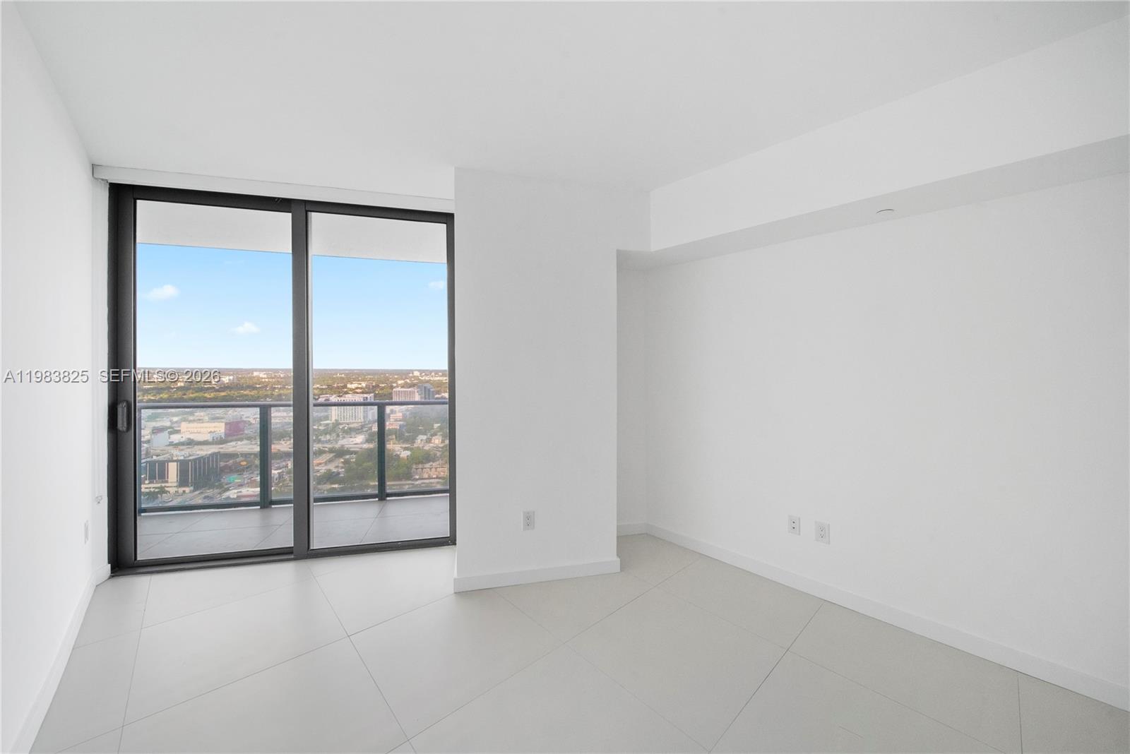 An empty room with white walls, tile flooring, and a sliding glass door to a balcony — 501 NE 31st St # 3110, Miami FL 33137, MIAMI, FL