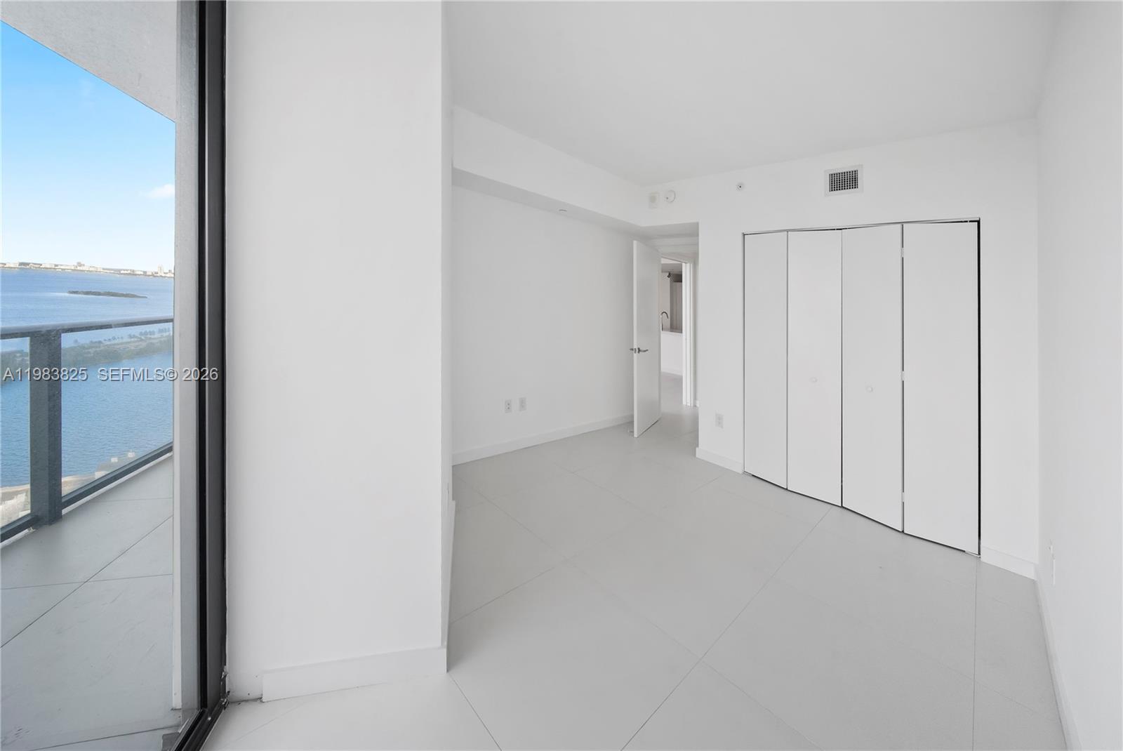 An empty room with white walls, tile flooring, a closet, and a balcony overlooking water — 501 NE 31st St # 3110, Miami FL 33137, MIAMI, FL