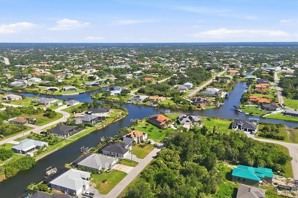 An aerial view shows residential houses situated along a network of narrow canals — 10099 LONG BRANCH STREET, PORT CHARLOTTE, FL