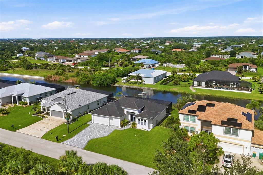 An aerial view of a suburban neighborhood featuring several houses along a canal — 10099 LONG BRANCH STREET, PORT CHARLOTTE, FL